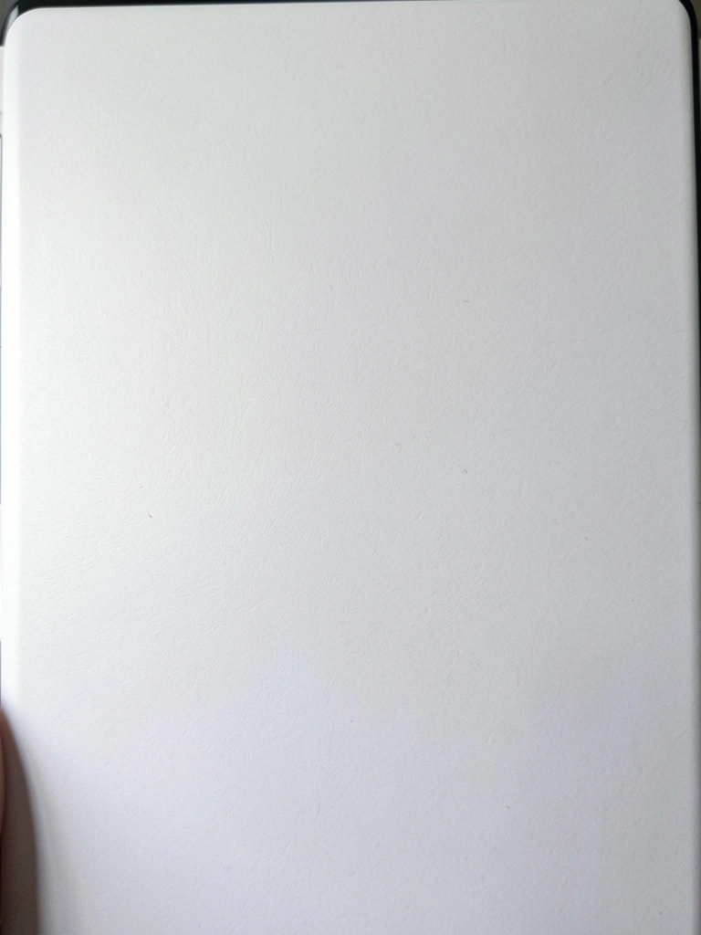 Pessoa segurando um caderno aberto com anotações ao lado de um notebook sobre uma mesa de madeira.